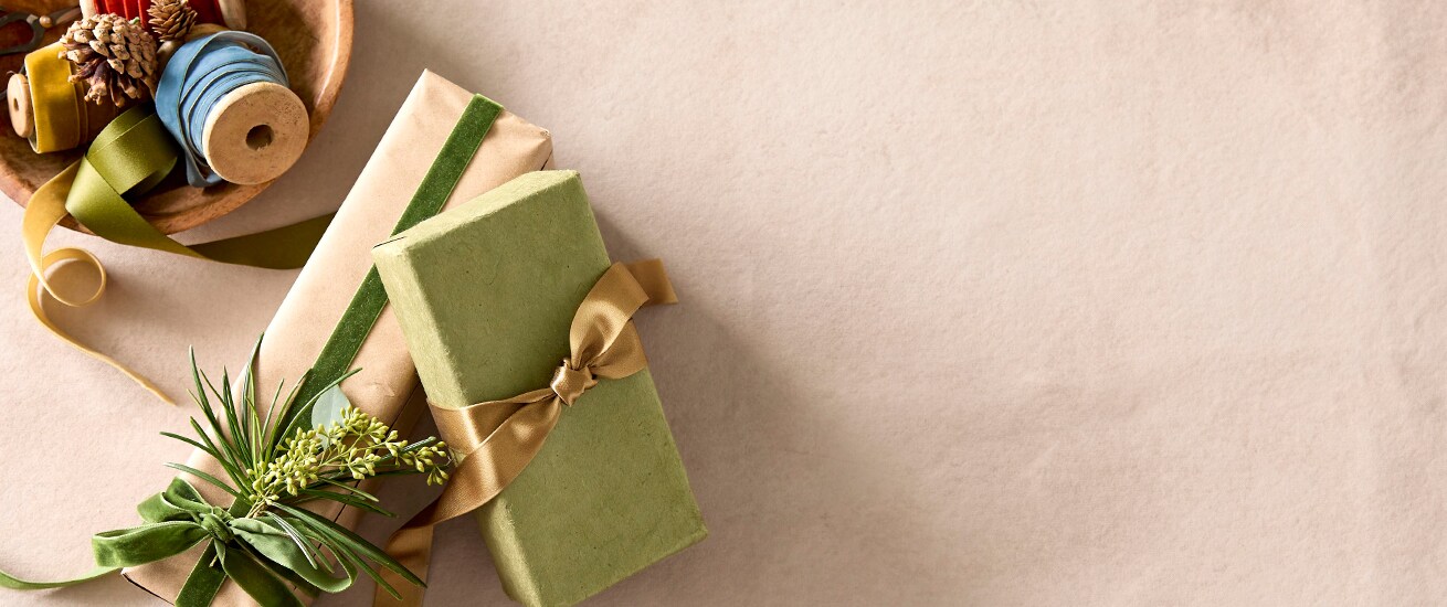Wrapped holiday gifts sit near a bowl of wrapping supplies.