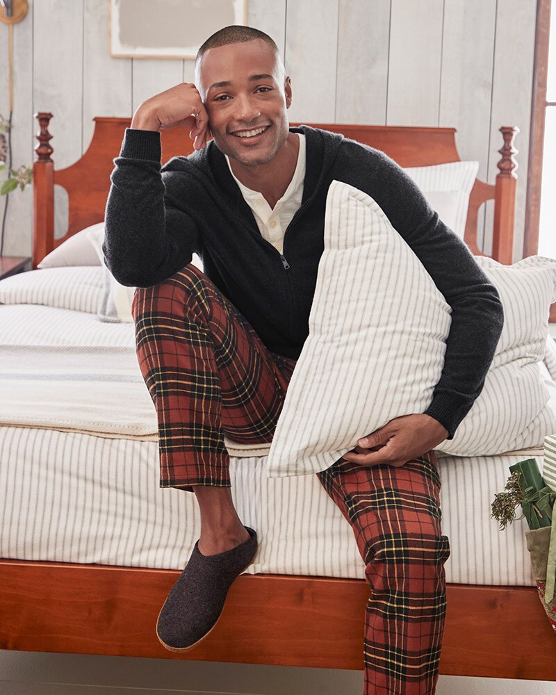 A man in a sleepshirt and plaid flannel pajama pants. Shop sleepwear.