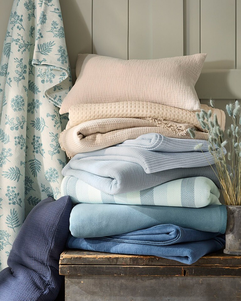 A stack of summer blankets in various colors and patterns. Shop blankets & throws.