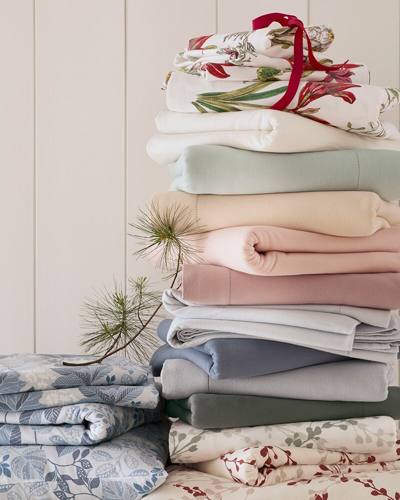 A stack of soft flannel sheets in solid colors and holiday prints. Browse all bedding.