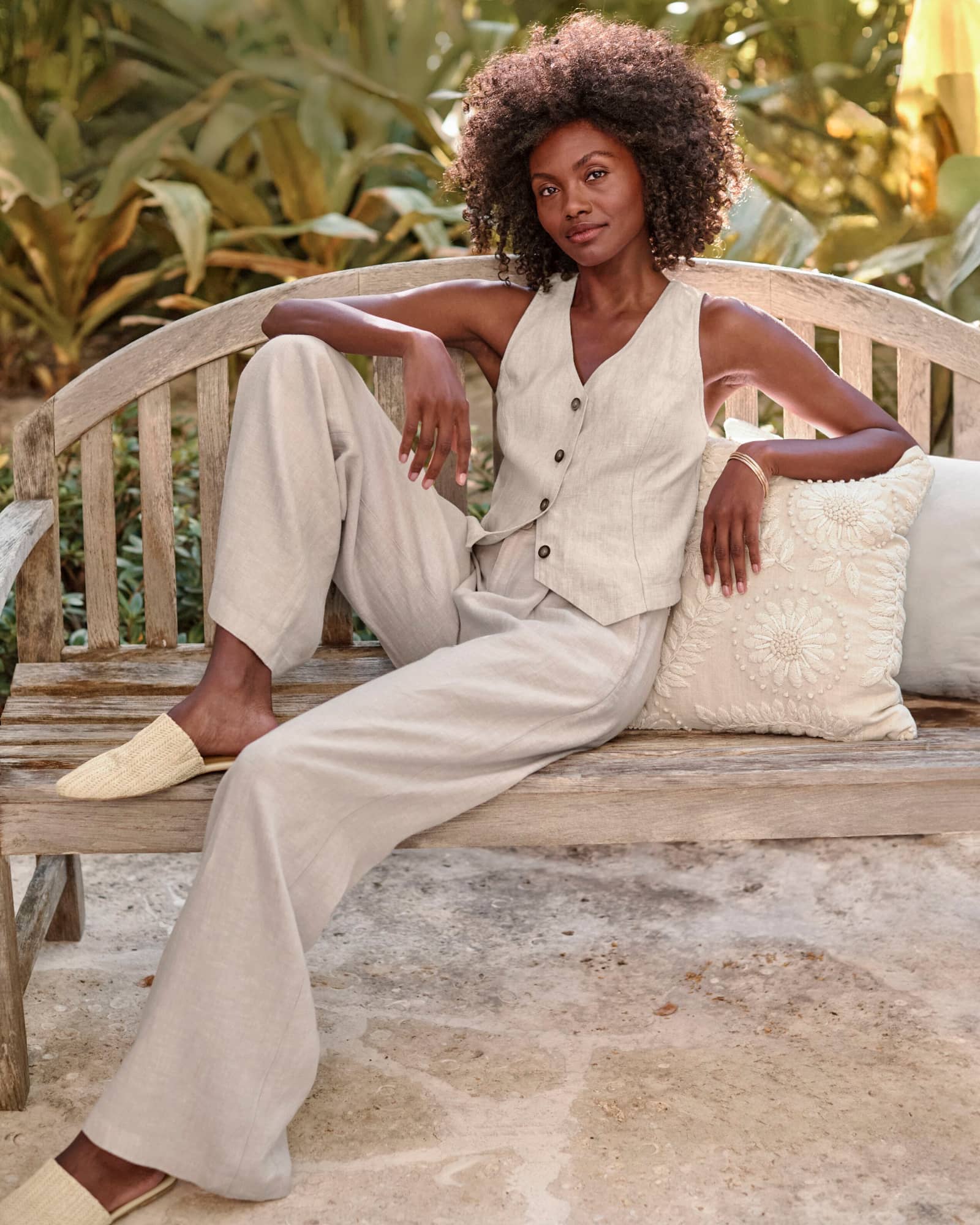 A woman in a linen vest and linen wide-leg trousers. Shop pants.